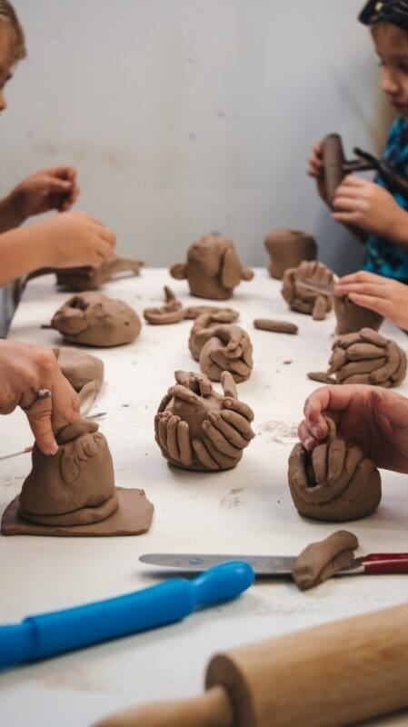 Children engaging in ceramic clay work, shaping and molding their creations with hands and tools.